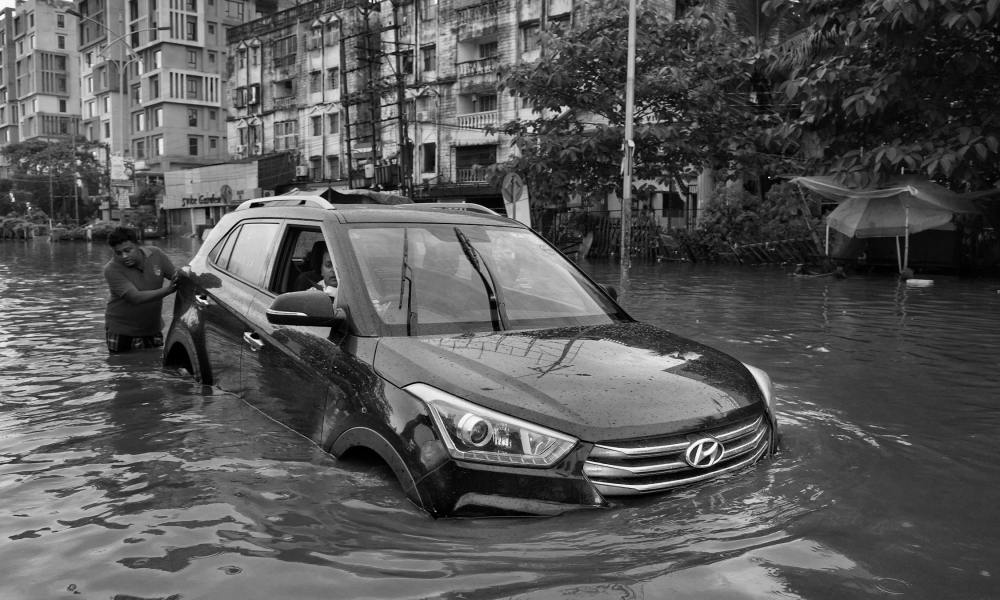 Man pushing car through flooded street