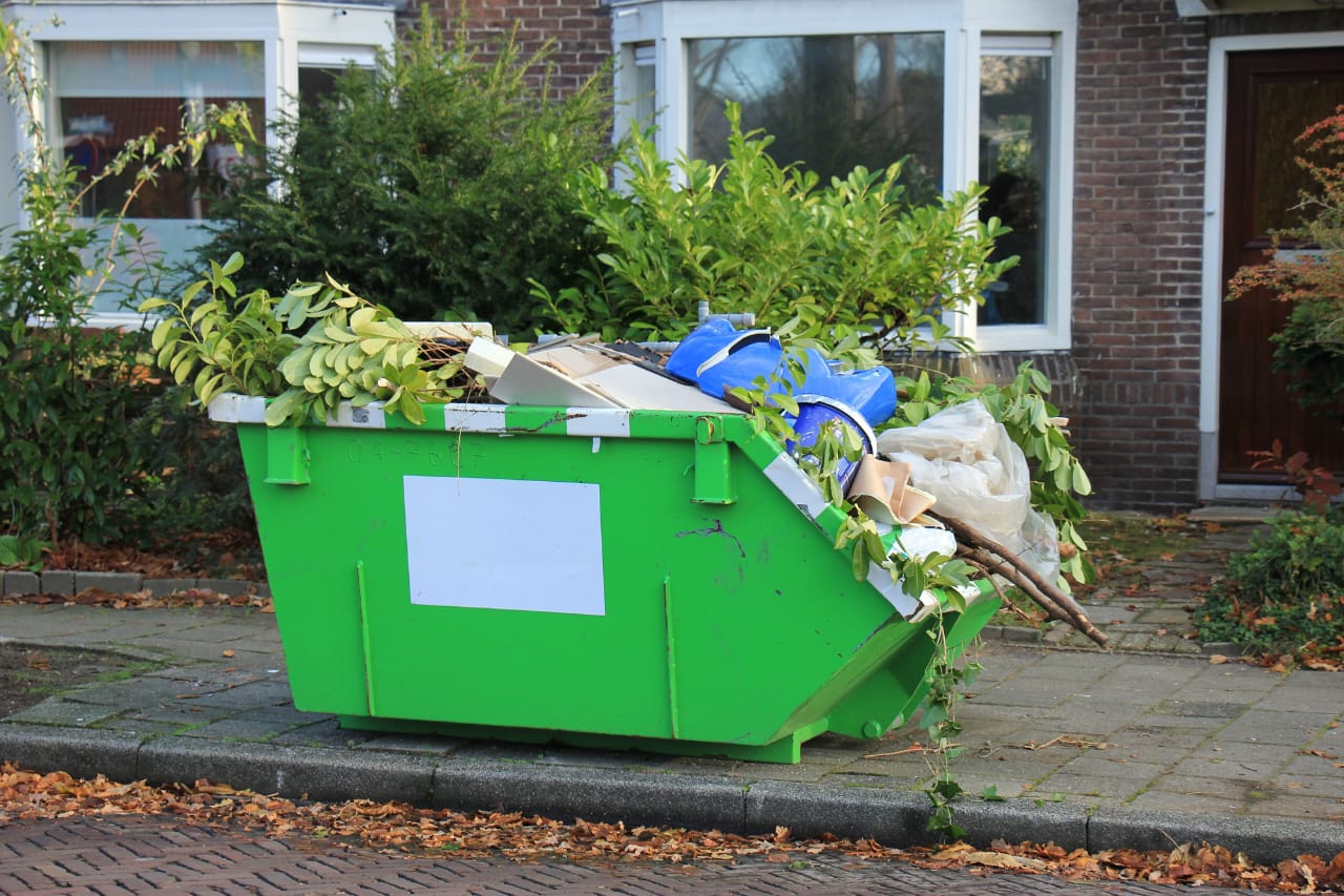 Green dumpster on sidewalk