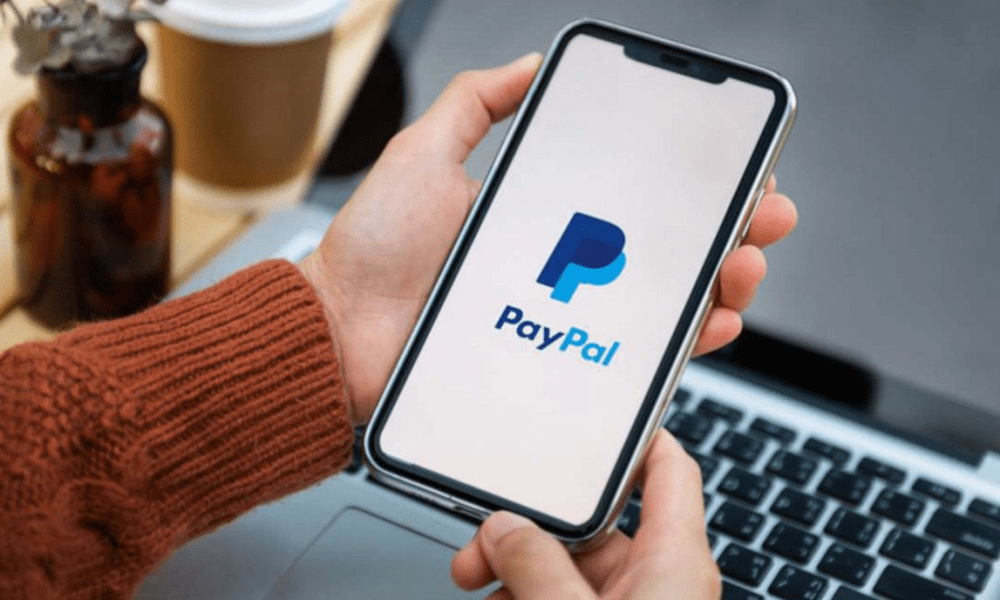 Hand holding phone displaying PayPal