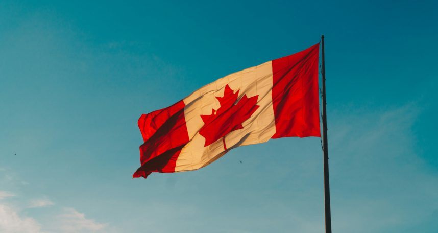 Canadian flag waves against blue sky