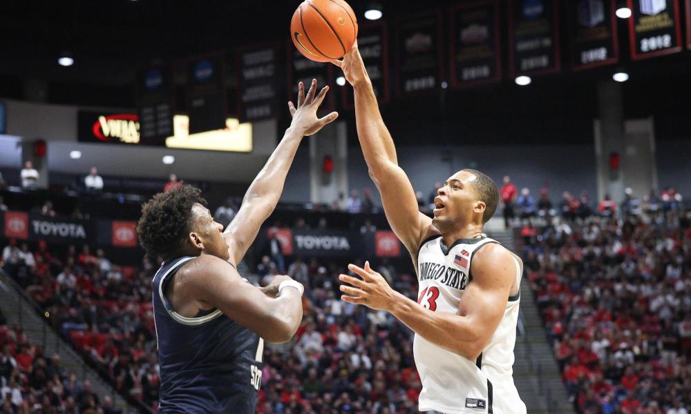 Player shoots basketball over defender