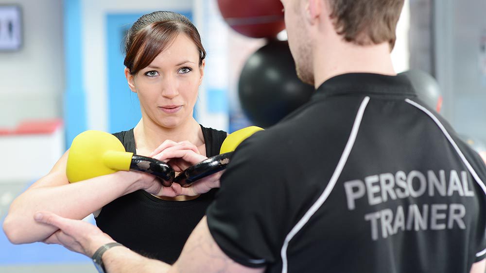 Female trainee weightlifting with instructor