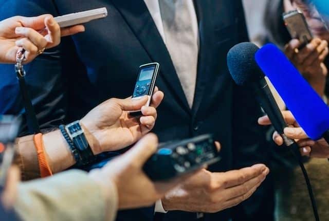 Sports reporters holding phones and microphones