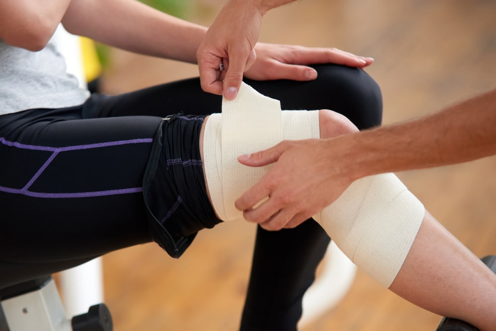 Athletic trainer taping patient's knee