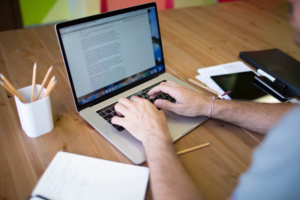 Person typing on content coordinator laptop