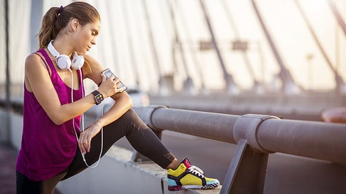 Woman with headphones sitting on bridge