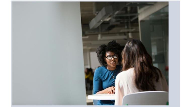 Two women meet at office desk