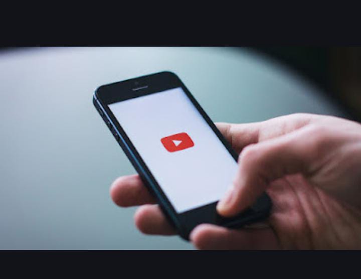 Hand holding smartphone showing YouTube