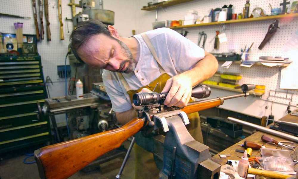 Gunsmith repairing rifle at workbench