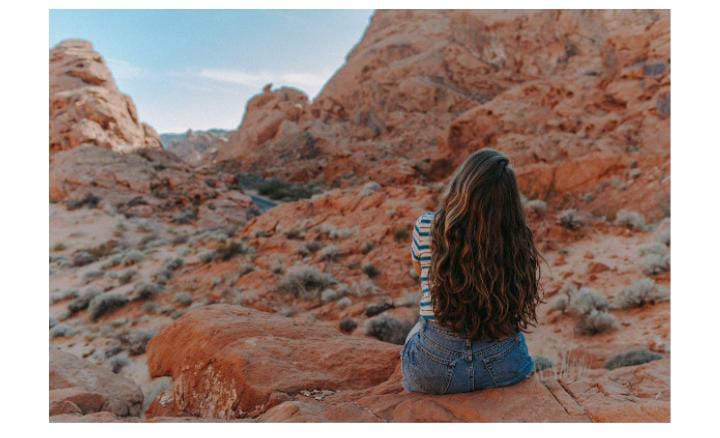 Woman sits on cliff edge